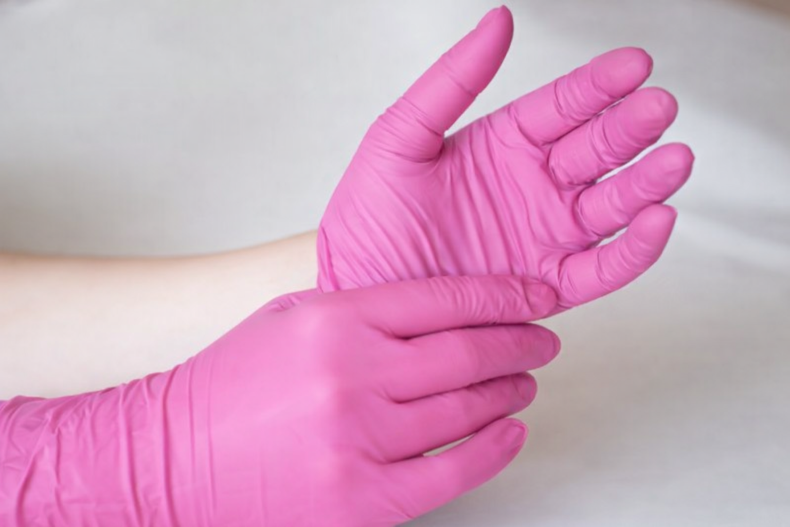 Clinician putting on pink medical gloves